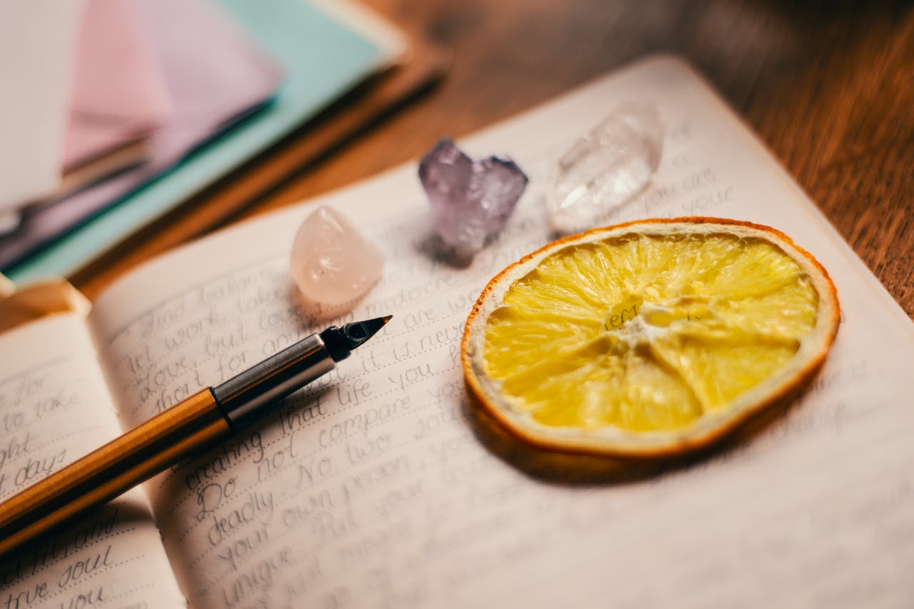 An artistic journal layout featuring a citrus slice, crystals, and a fountain pen for creative inspiration.
